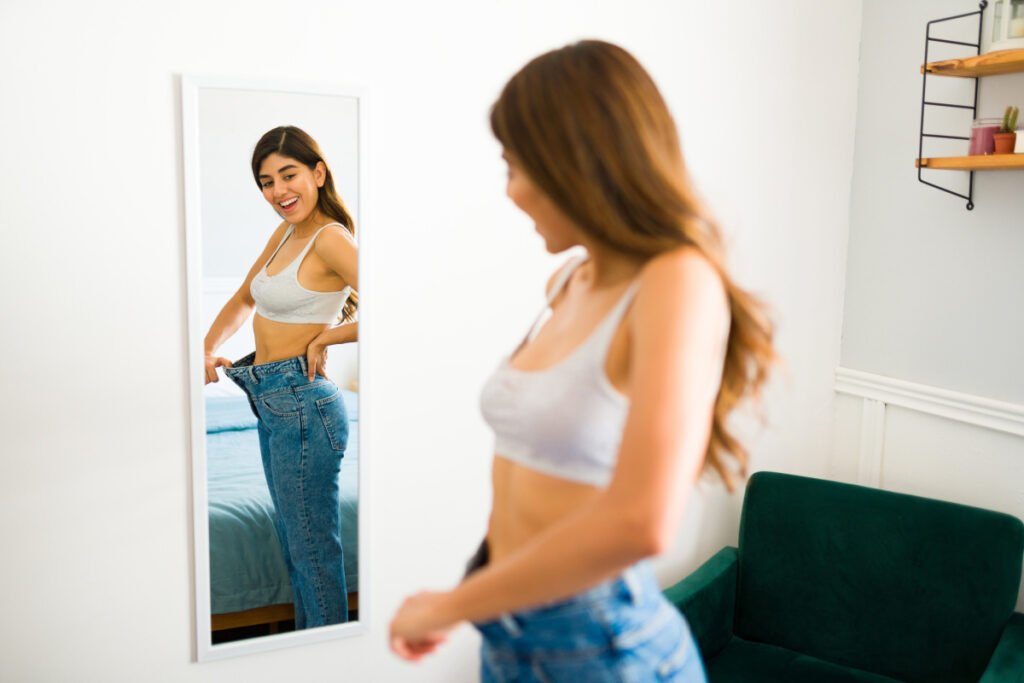 Woman looking in mirror after losing weight with The Skinny Shot semaglutide injections