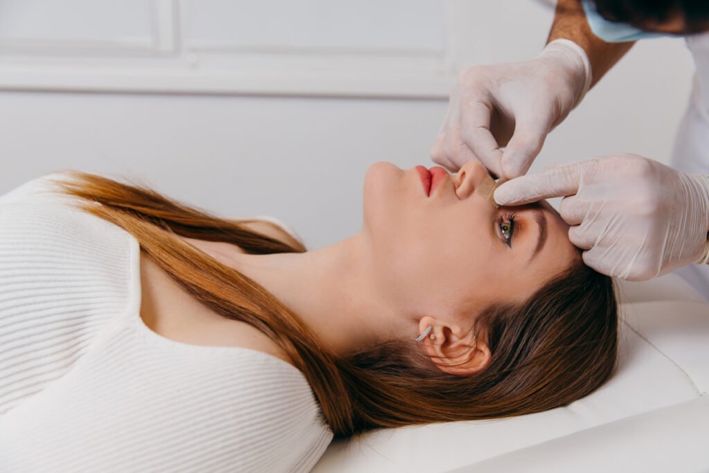 Woman with nose bandages talking to facial plastic surgeon